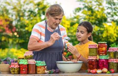 Women with jar preserved vegetables for the winter mother and daughter. Selective focus. Food.