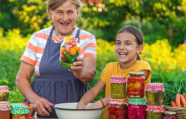 Women with jar preserved vegetables for the winter mother and daughter. Selective focus. Food.