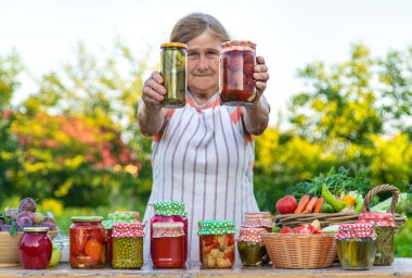 Senior woman preserving vegetables in jars. Selective focus. Food.
