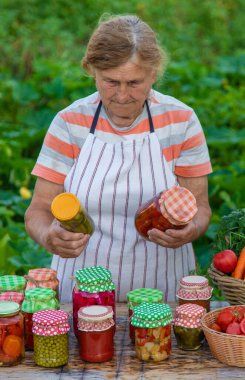 Senior woman preserving vegetables in jars. Selective focus. Food.