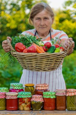 Senior woman preserving vegetables in jars. Selective focus. Food.