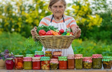 Senior woman preserving vegetables in jars. Selective focus. Food.