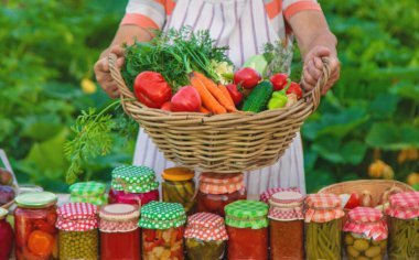 Senior woman preserving vegetables in jars. Selective focus. Food.