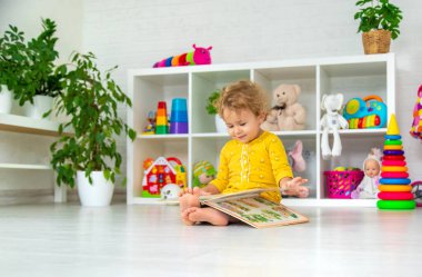 Children are reading a book in the room. Selective focus. Kid.