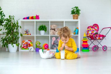 Child drink milk in the room. Selective focus. Kid.
