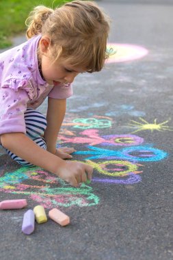 Çocuklar asfalta tebeşirle resim çiziyor. Seçici odaklanma. Çocuk.