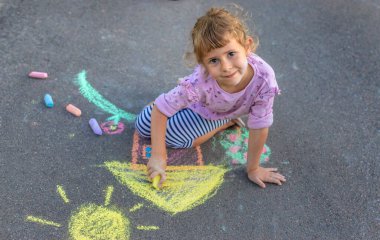 Çocuklar asfalta tebeşirle resim çiziyor. Seçici odaklanma. Çocuk.