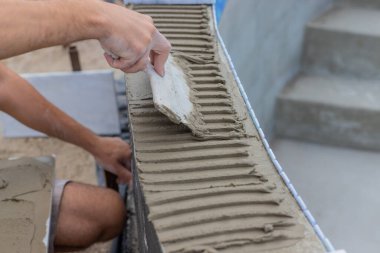 Bir teknisyen yüzme havuzuna fayanslar serer. Seçici odaklanma. insanlar.