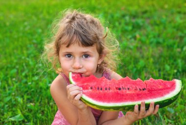 Bir çocuk parkta bir karpuz yiyor. Seçici odaklanma. Çocuk.