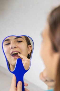 Dişçide bir çocuk aynada dişlerini inceliyor. Seçici odaklanma. Çocuk.