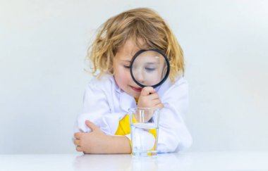 Bir çocuk suyu büyüteçle inceler. Seçici odaklanma. çocuk.