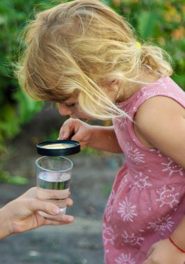 Bir çocuk büyüteçle suya bakar. Seçici odaklanma. çocuk.