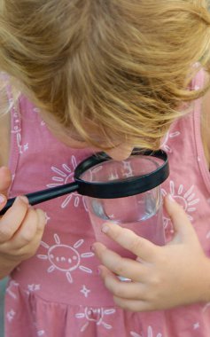 Bir çocuk büyüteçle suya bakar. Seçici odaklanma. çocuk.