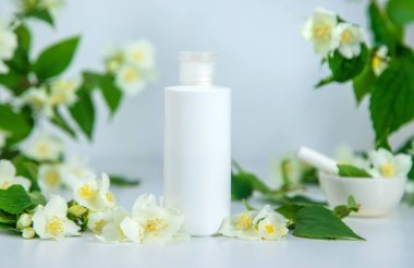 Yasemin arka planında bir şişe kozmetik ürünü. Seçici odaklanma. Doğa.