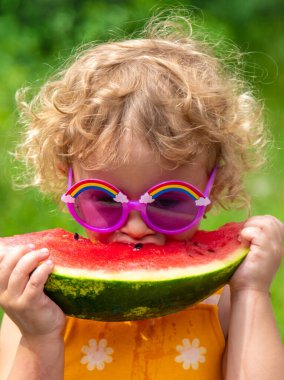 A child eats watermelon in the park. Selective focus. Kid.