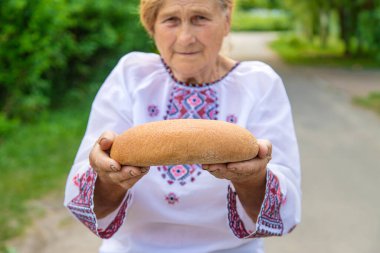 Elinde Ukrayna ekmeği olan bir büyükanne. Seçici odaklanma. Yiyecek..