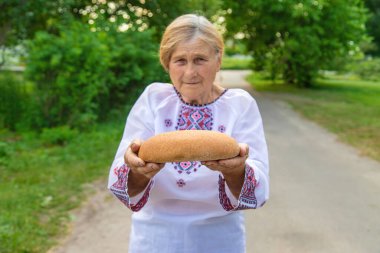 Elinde Ukrayna ekmeği olan bir büyükanne. Seçici odaklanma. Yiyecek..