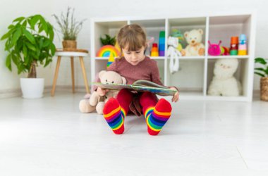 Bir çocuk evde bir kitaba bakar. Seçici odaklanma. Çocuk.