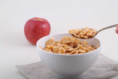 Mısır ve pirinç gevreği bir kaşık ve bir beyaz backg üzerinde kırmızı elma