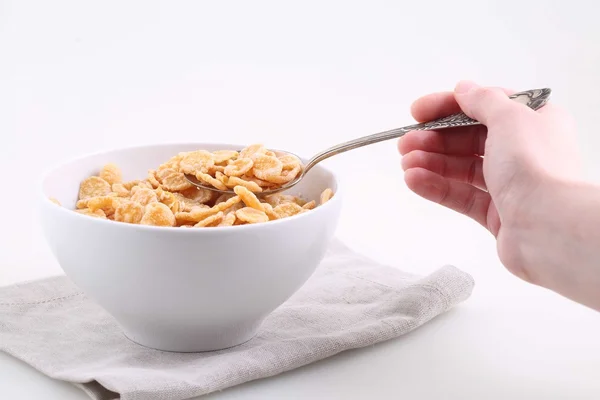 A mão feminina segura uma colher com arroz e flocos de milho — Fotografia de Stock