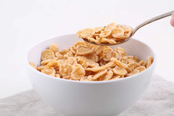 Corn and rice flakes in a spoon on a white background