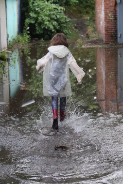 bir su birikintisi çalışan kız kauçuk botlar