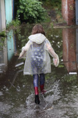 bir su birikintisi çalışan kız kauçuk botlar