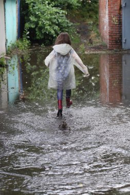 bir su birikintisi çalışan kız kauçuk botlar