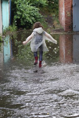 bir su birikintisi çalışan kız kauçuk botlar