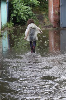 bir su birikintisi çalışan kız kauçuk botlar