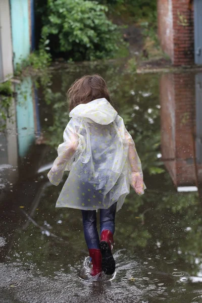 bir su birikintisi çalışan kız kauçuk botlar