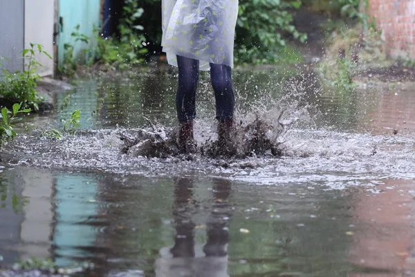 Girl in rubber boots jumping in a puddle — Stock Photo, Image