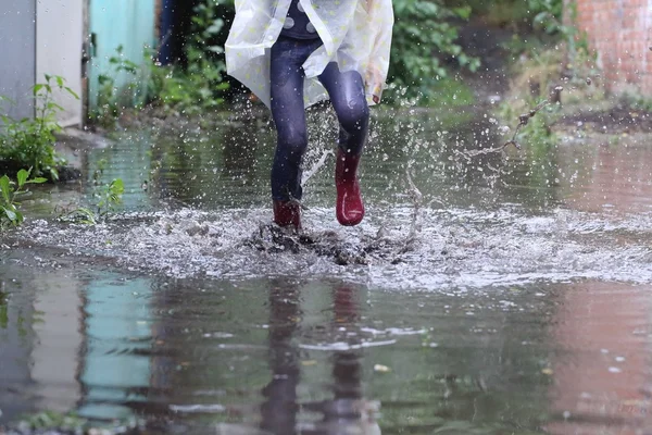 ゴムの女の子は、水たまりにジャンプ ブーツします。 — ストック写真