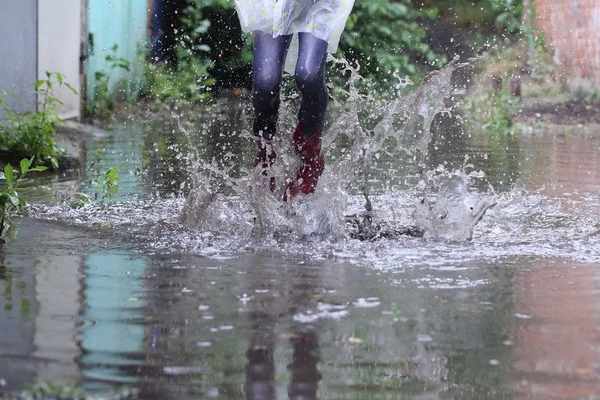 Girl in rubber boots jumping in a puddle — Stock Photo, Image