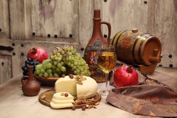 Vin i ett genomskinligt glas, druvor och rött granatäpple — Stockfoto