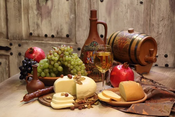 Wine in a clay jug and fruit on a wooden table — Stock Photo, Image