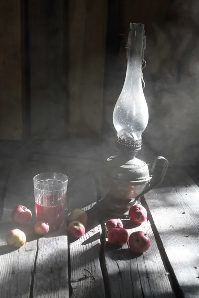 Äpplen, saft och en fotogenlampa på bordet i — Stockfoto