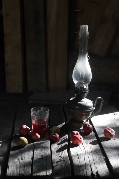 Jabłka, sok i lampa naftowa na stole w — Zdjęcie stockowe