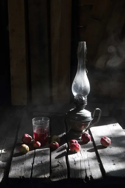 Керосиновая лампа, компот Apple и яблоки на деревянном столе — стоковое фото
