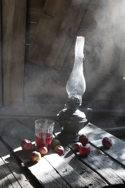 Jabłka, sok i lampą naftową na stole w starej cottag — Zdjęcie stockowe