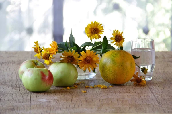 melon, apples and a bouquet of yellow daisies