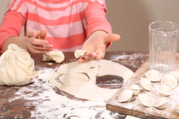 Kinder handen met een deeg voor molding knoedels — Stockfoto