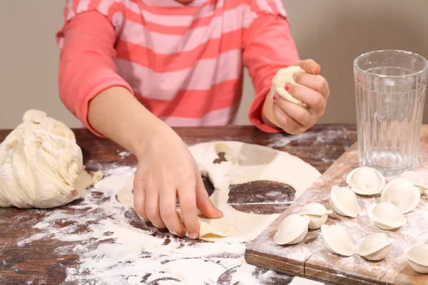 Девушка делает пельмени, тесто в руках ребенка — стоковое фото
