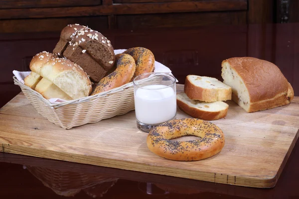 Bollo con pasas, rosquillas y pan y un vaso de leche — Foto de Stock