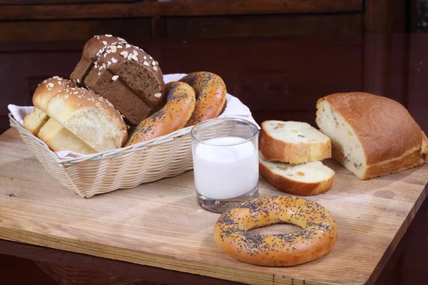 Bollo con pasas, rosquillas y pan y un vaso de leche — Foto de Stock