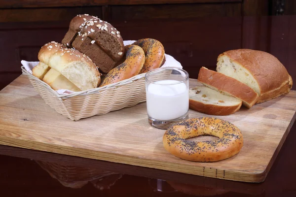 Bollo con pasas, rosquillas y pan y un vaso de leche — Foto de Stock