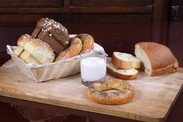 Bollo con pasas, rosquillas y pan y un vaso de leche — Foto de Stock