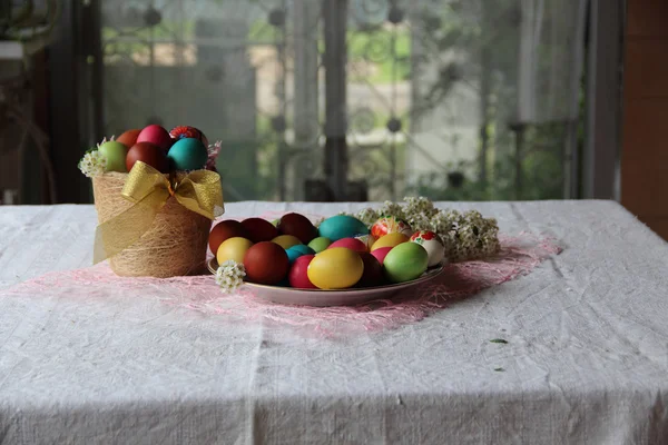 Masanın üzerinde bir sepet içinde boyalı yumurta — Stok fotoğraf