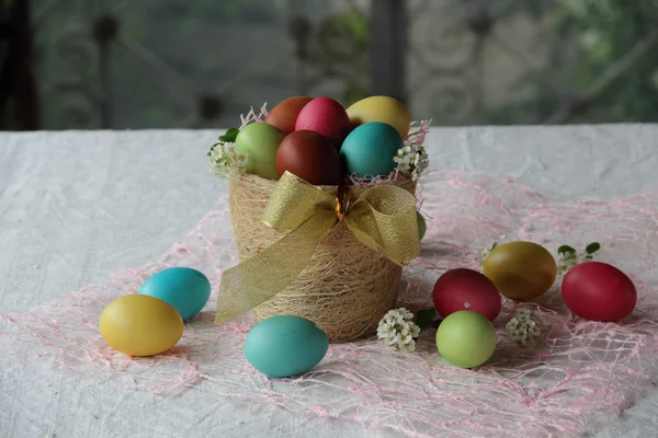 Bemalte Eier in einem Korb auf dem Tisch — Stockfoto