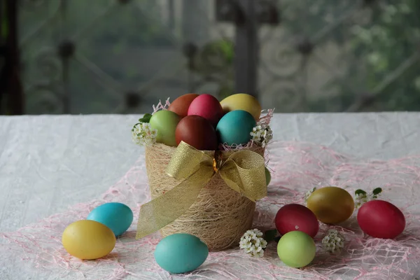 Masanın üzerinde bir sepet içinde boyalı yumurta — Stok fotoğraf
